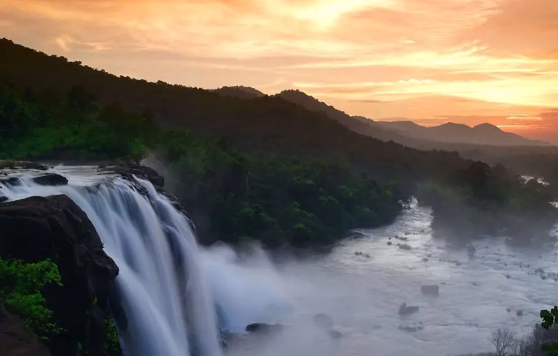 Athirapally Waterfalls in Kerala surrounded by lush green forests and scenic tropical landscape during monsoon season